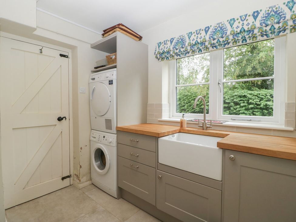 A utility room with a washing machine and sink at St. Marys House Church Westcote near Bledington
