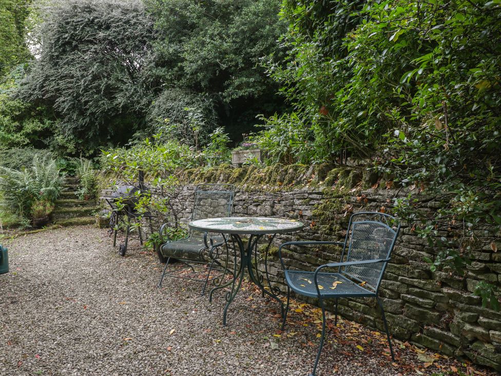 A garden with a table and chairs near a stone wall at St. Marys House Church Westcote near Bledington