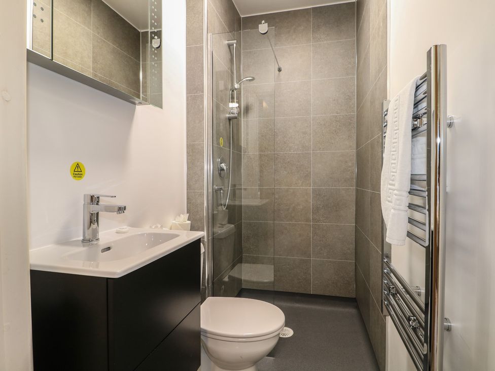 A bathroom with a sink, toilet, shower, mirror, and towel rail at Bedroom 1 in Littlehampton