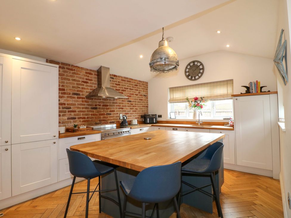 A kitchen with wooden counter and stools at Farm View House in Somerby