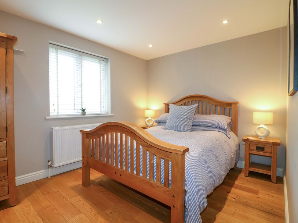 A bedroom with a wooden bed frame and nightstand at Farm View House Somerby