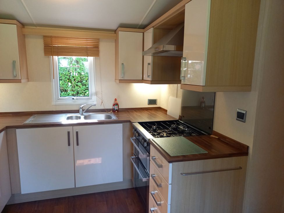 A kitchen with a sink stove and cabinets at Emma No.6 Llandegfan