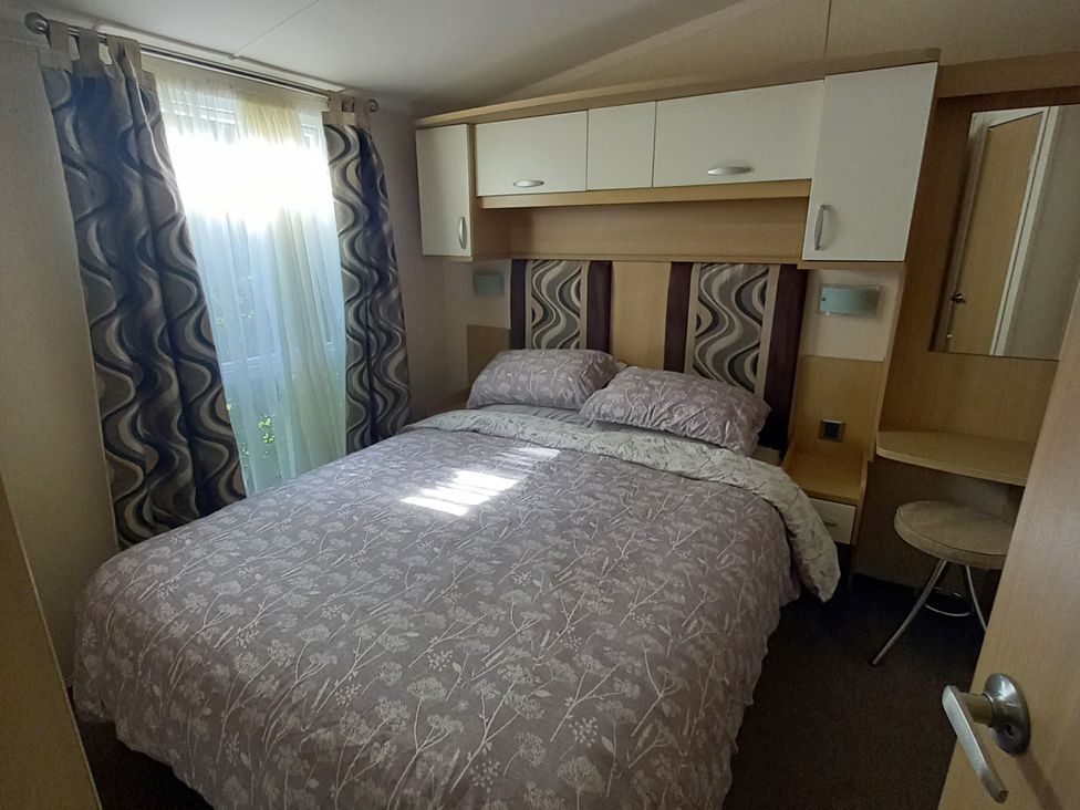 A bedroom with a bed and a mirror at Emma No.6 in Llandegfan