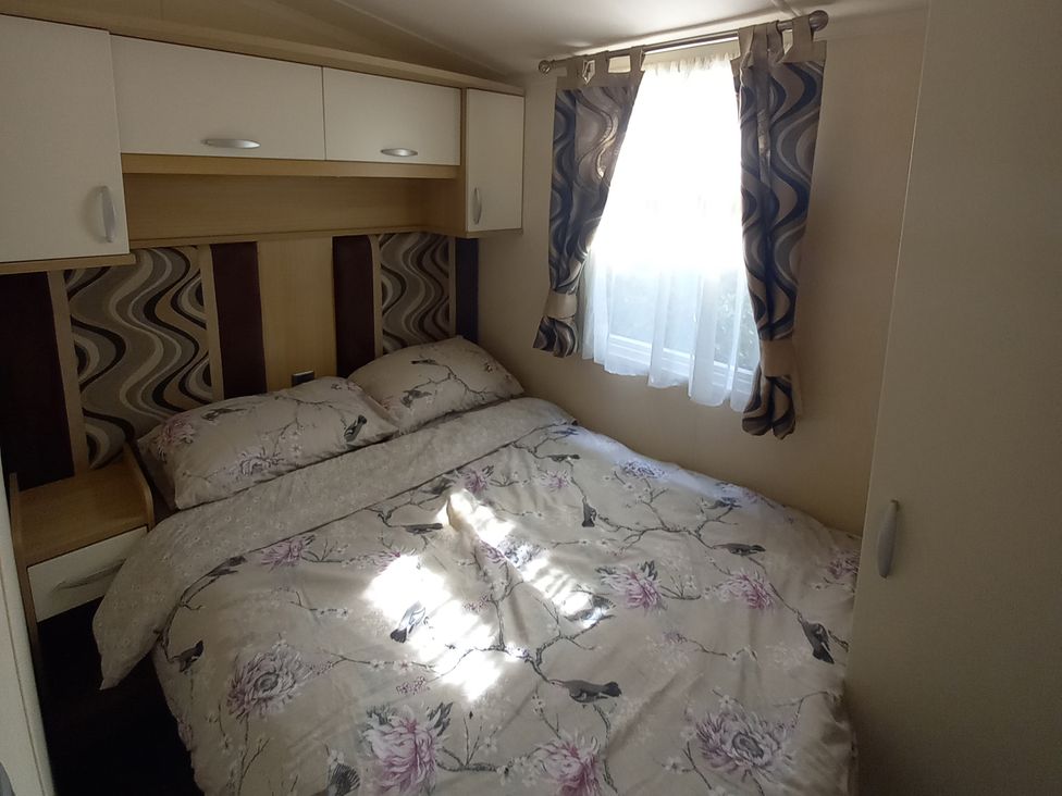 A bedroom with a bed and shelves at Emma No.6 Llandegfan
