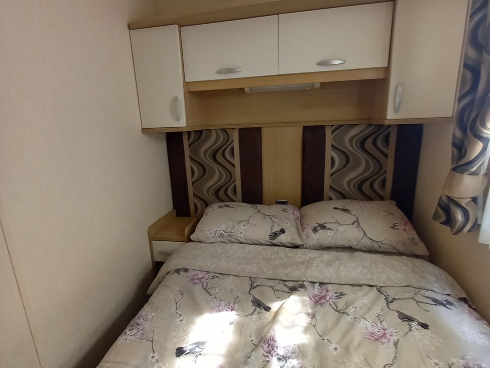 A bedroom with a bed and bedside cabinet at Emma No.6 in Llandegfan