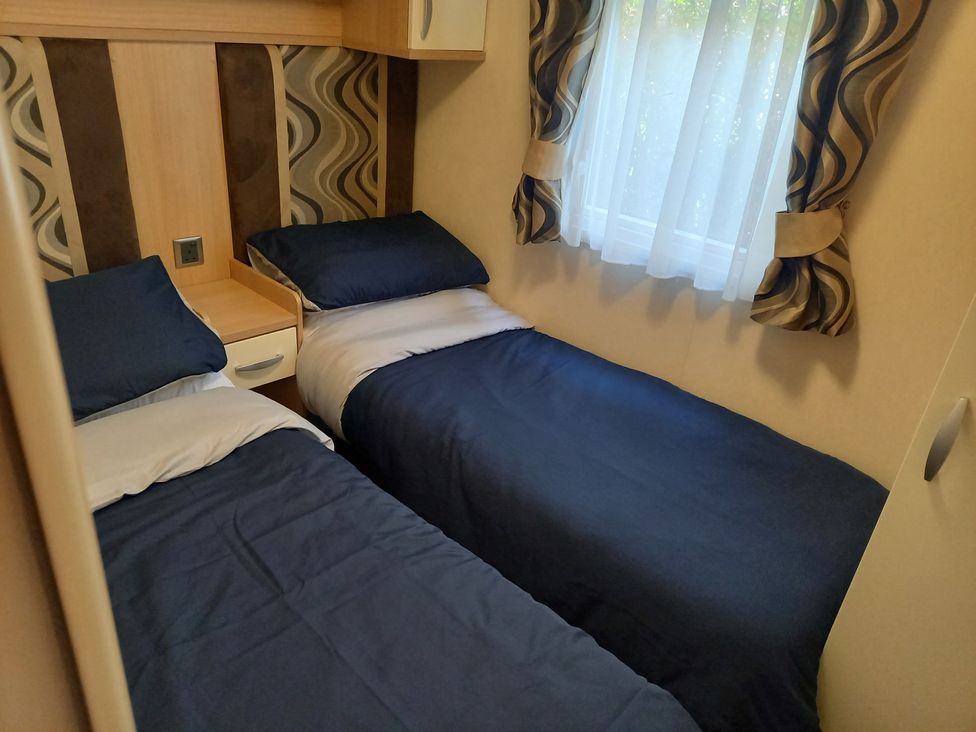 A bedroom with two beds and a window at Emma 6 in Llandegfan