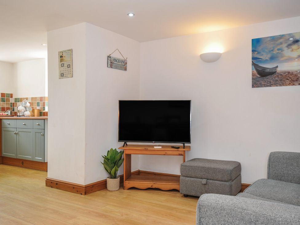 A living room with a television and a sofa at Norvys in Bossiney