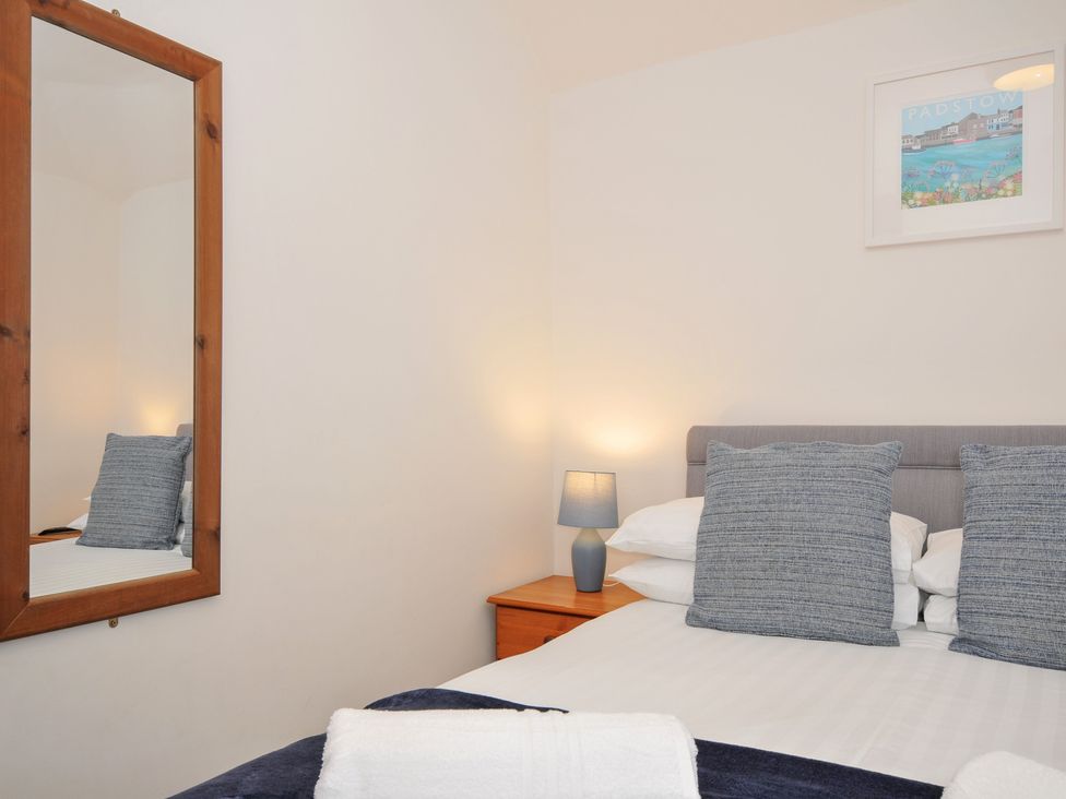 A bedroom with a bed, pillows, and a mirror at Norvys in Bossiney