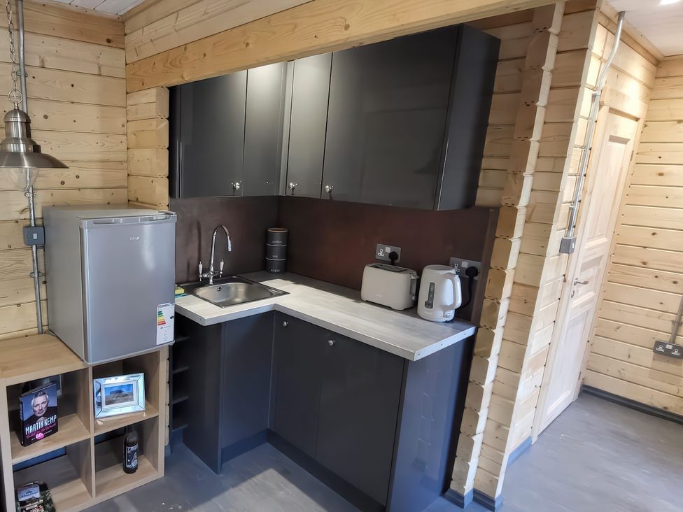A kitchen with a fridge, sink, and kitchen cabinets at Sea La Vie in Perranporth