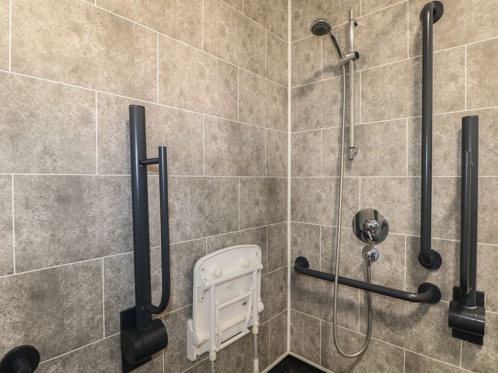 A shower room with grab bars and a folding shower seat at Bedroom 4 in Littlehampton