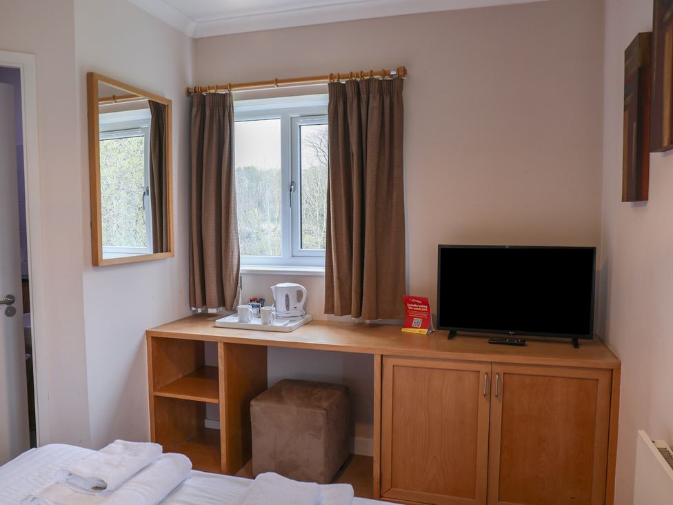 A bedroom with a mirror and desk with a kettle and television at Bedroom 33 