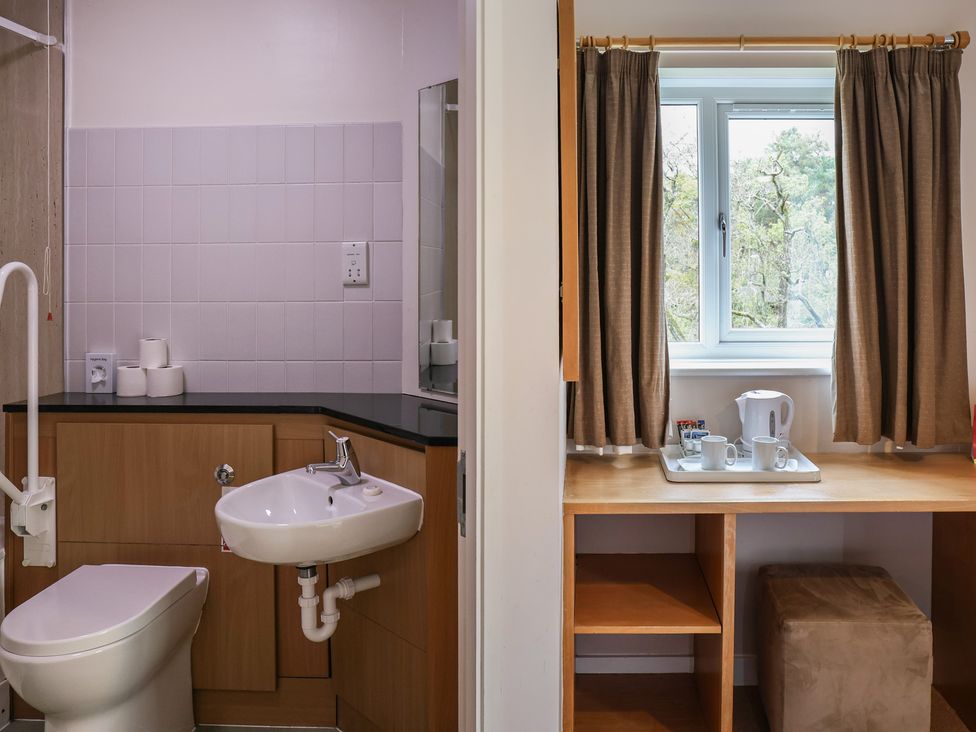A bathroom with a sink and toilet and a workspace with a coffee tray at Bedroom 21 in Penrith