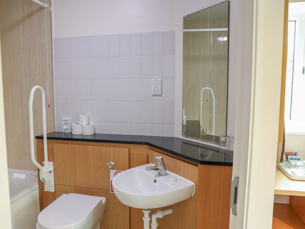 A bathroom with a sink, toilet, and mirror at Bedroom 21 in Penrith
