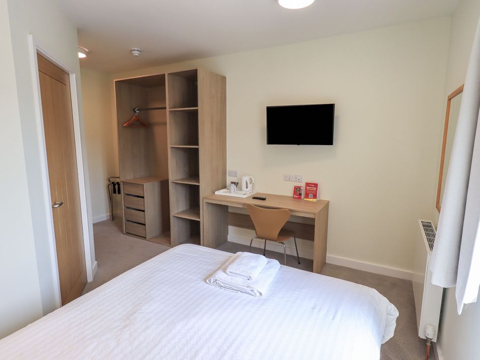 A bedroom with a bed, wardrobe, desk, and TV at Eamont Park First-floor Double Bedroom in Penrith