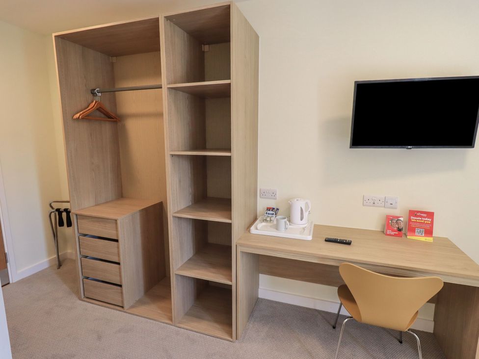A bedroom with a wardrobe, table, chair, and television at Eamont Park First-floor Double Bedroom in Penrith