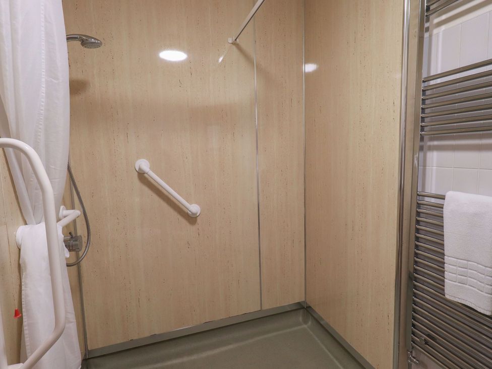 A shower with grab bars and towels at Eamont Park First-floor Double Bedroom in Penrith