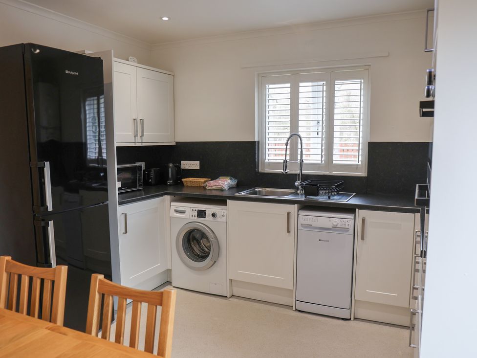 A kitchen with refrigerator, washing machine, sink and dishwasher at Bungalow 19 Eamont Park Penrith
