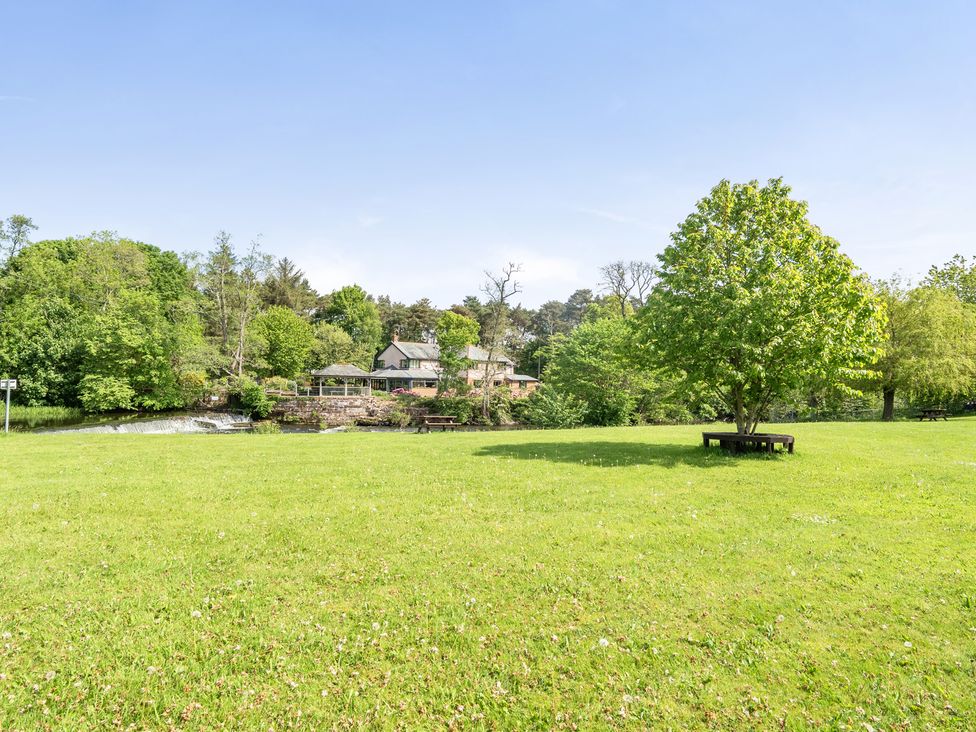A park with grass, a tree, river, and a house at Jubilee Bungalow Pet Friendly Sleeps 4 in Penrith
