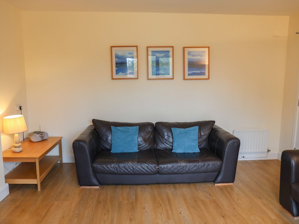 A living room with a sofa, lamp, and pictures on the wall at Bungalow 14 Eamont Park in Penrith