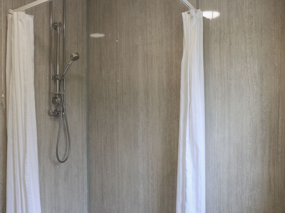 A shower with a shower head and curtain at Bungalow 14 Eamont Park Penrith