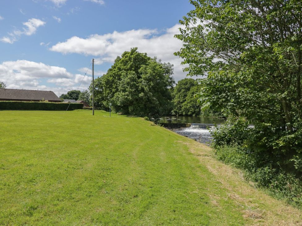 A grassy area with trees near a river at Bungalow 14 Eamont Park Penrith