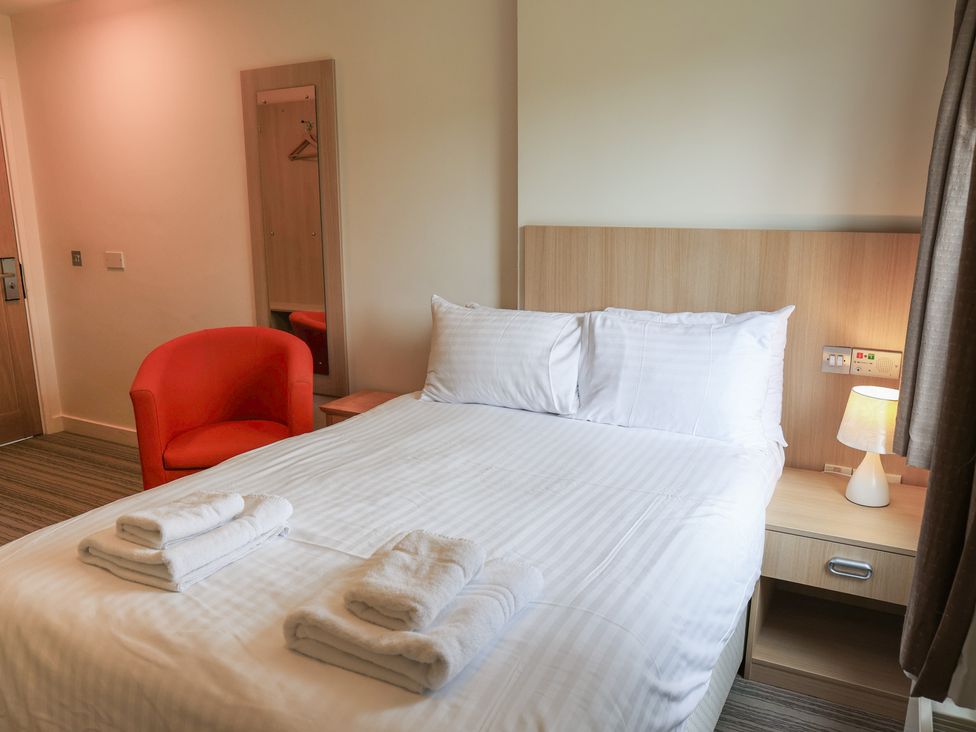 A bedroom with a bed and chair at Bedroom 7 in Penrith