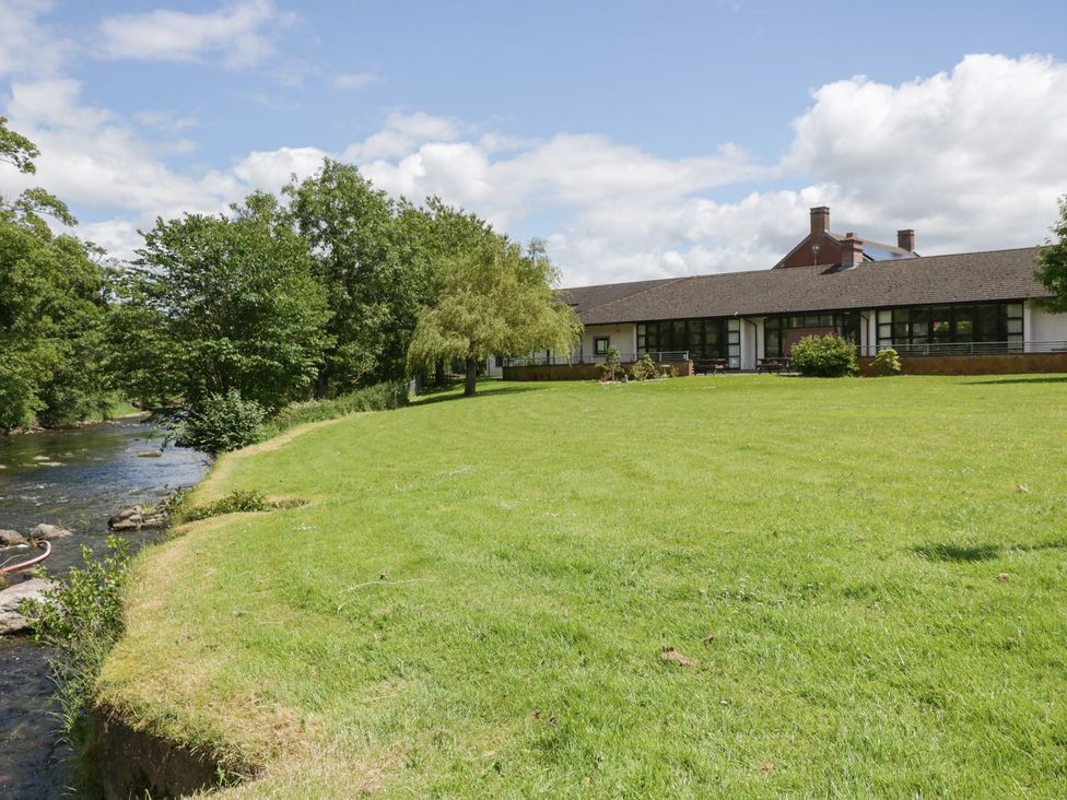 An outdoor area with a building, grass, trees, and a river at Penrith