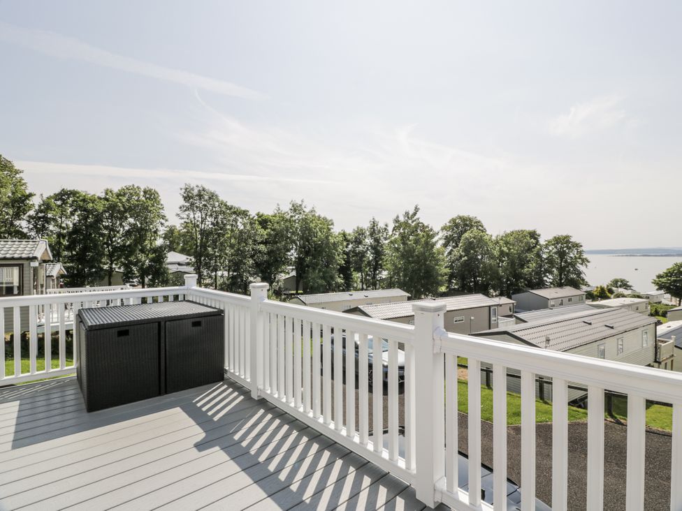 A deck with an outdoor storage container and a view of mobile homes at Number 42 in Wemyss Bay