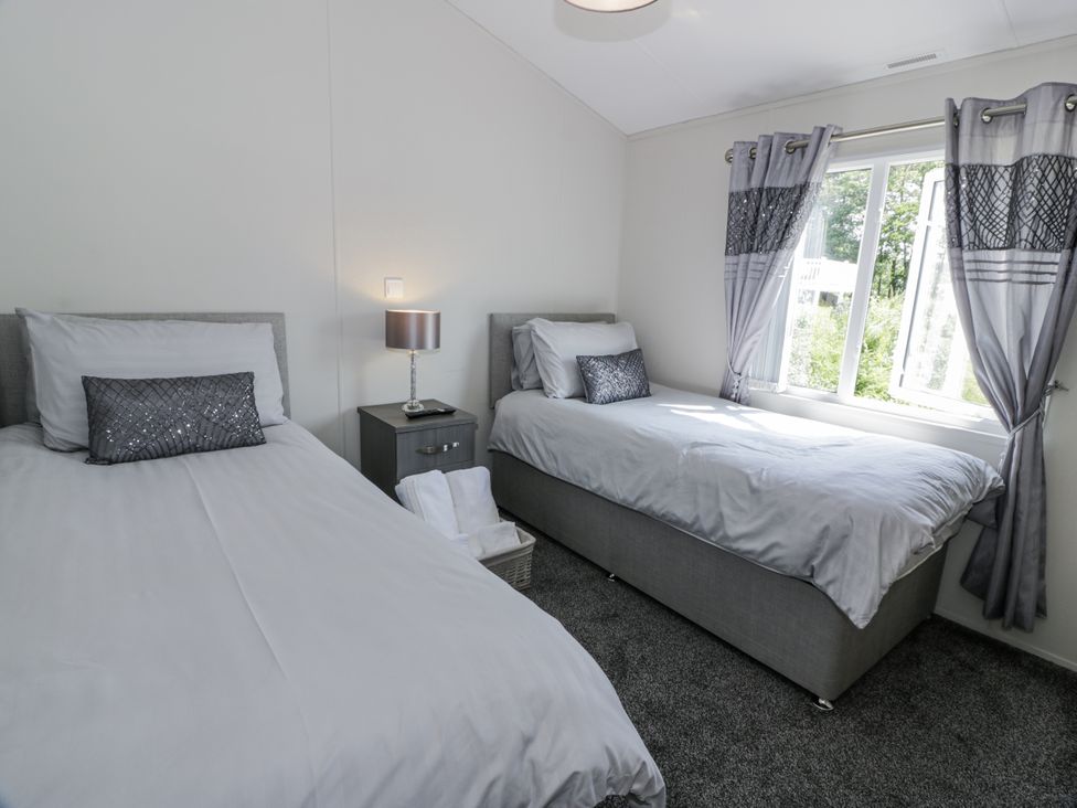 A bedroom with two beds and a lamp at Number 42 in Wemyss Bay