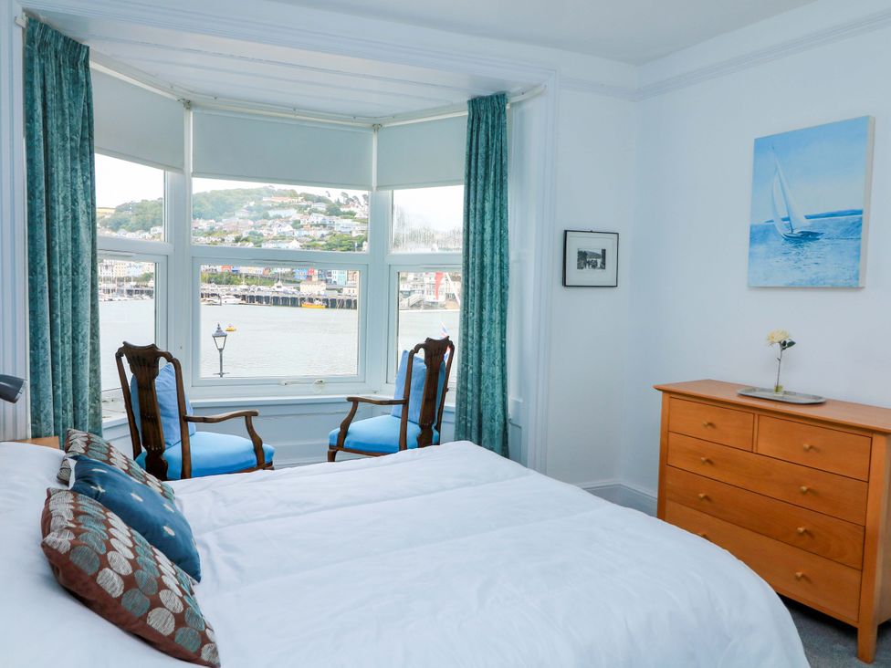 A bedroom with a bed and chairs near a window at Castleview Apartment, 21 South Embankment, Dartmouth