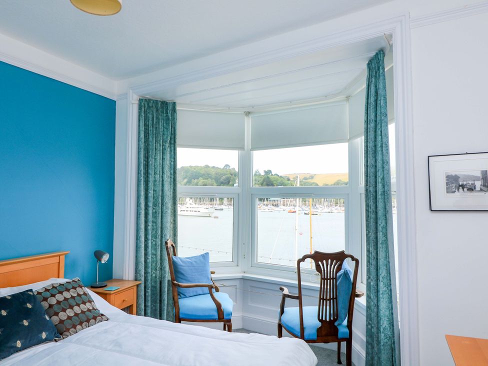 A bedroom with a bed and chairs overlooking a marina at Castleview Apartment, 21 South Embankment, Dartmouth