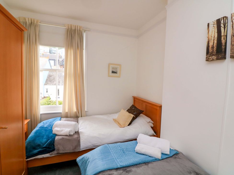 A bedroom with two beds and a wardrobe at Castleview Apartment, 21 South Embankment, Dartmouth