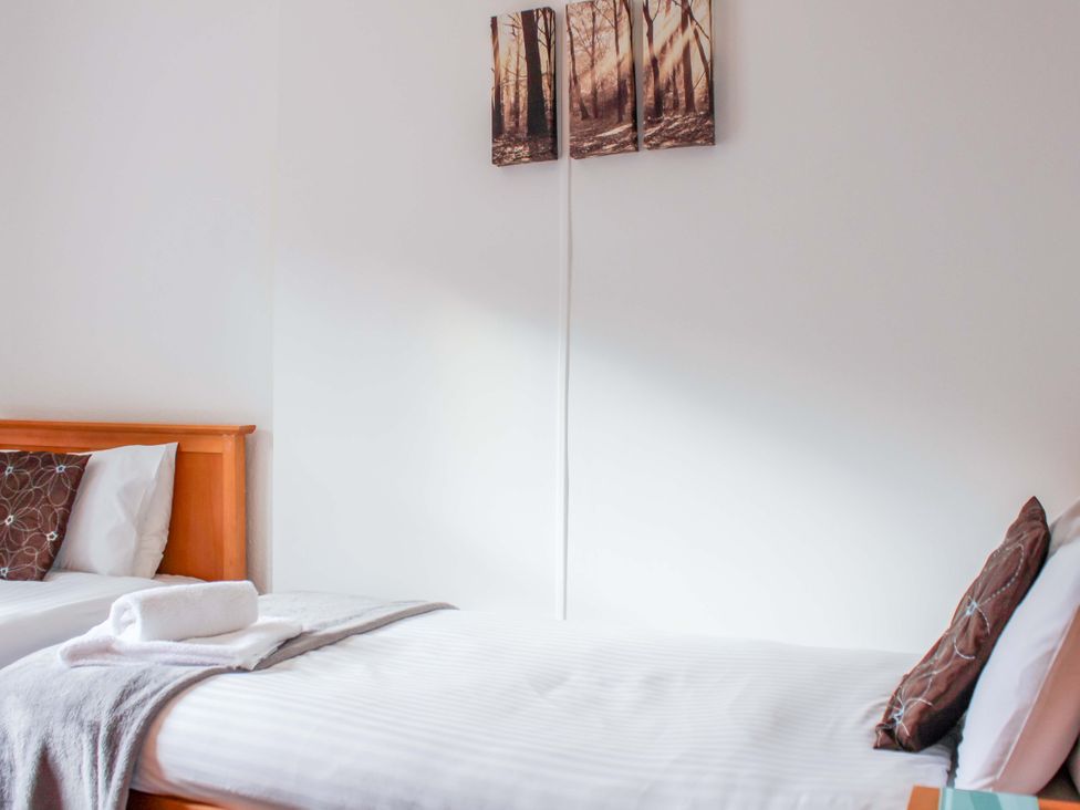 A bedroom with two beds and wall art at Castleview Apartment, 21 South Embankment Dartmouth