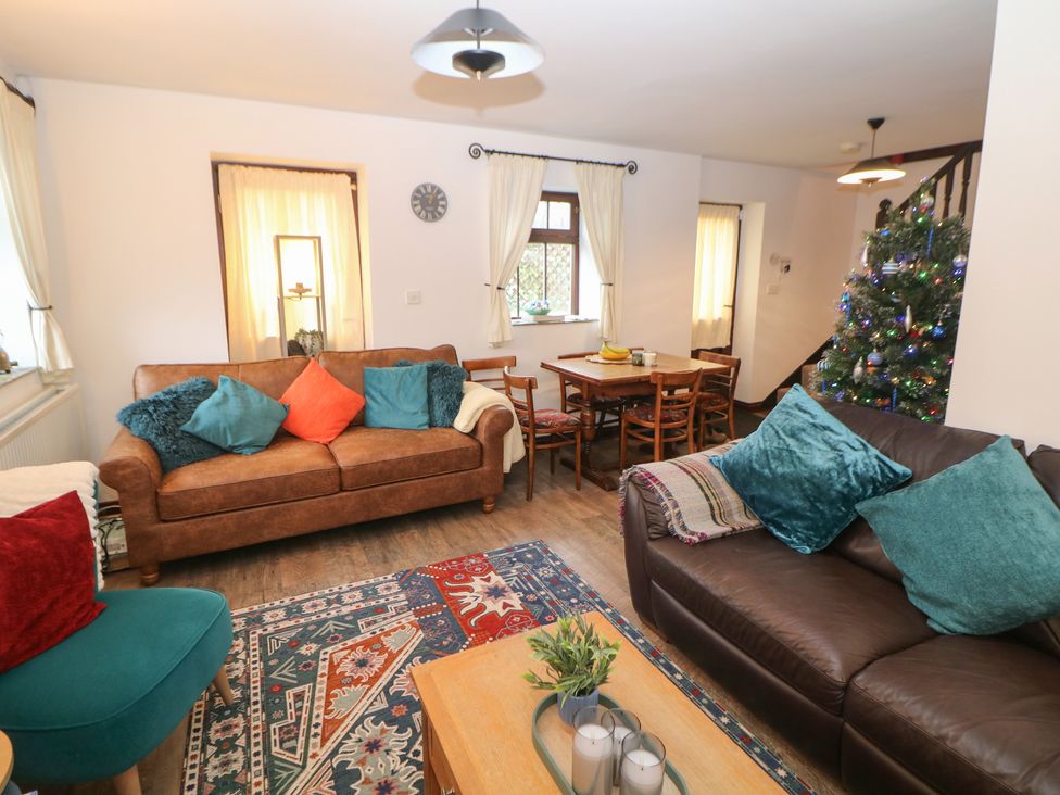 A living room with a sofa, armchair, dining table and Christmas tree at Win Hill View Cottage in Hope Valley