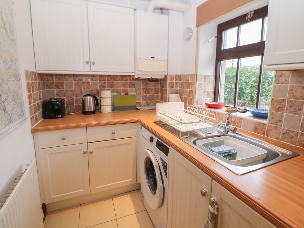 A kitchen with a sink, washing machine, and appliances at Win Hill View Cottage in Hope Valley