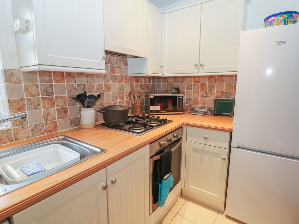 A kitchen with cabinets, sink, stove, refrigerator, and microwave at Win Hill View Cottage, Hope Valley