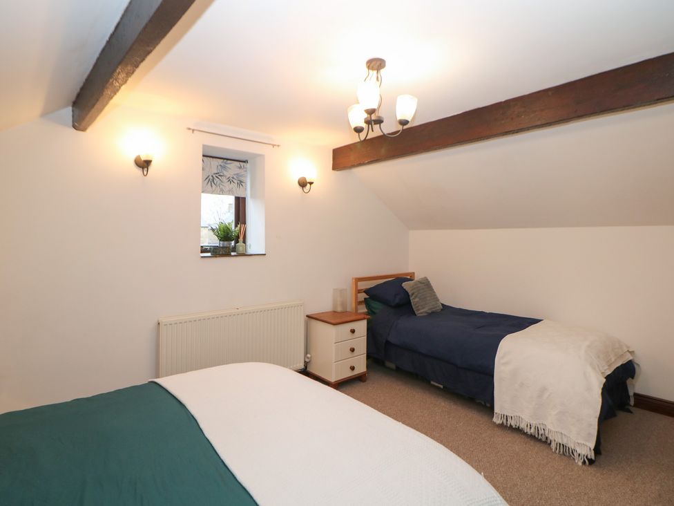A bedroom with two beds and a window at Win Hill View Cottage in Hope Valley