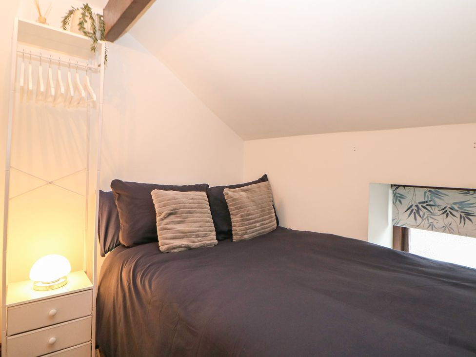 A bedroom with a bed and shelf at Win Hill View Cottage in Hope Valley
