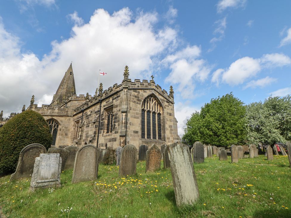 A church surrounded by grave stones and trees at Win Hill View Cottage in Hope Valley
