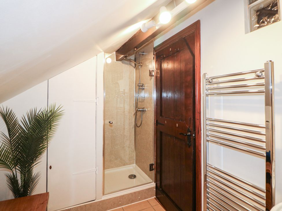 A bathroom with a shower, towel rail, and storage at Win Hill View Cottage in Hope