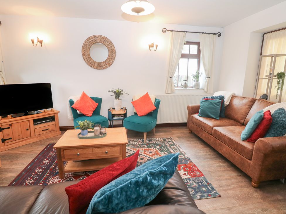 A living room with a television and sofa at Win Hill View Cottage in Hope