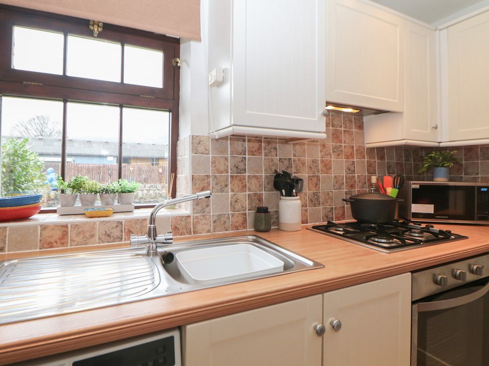 A kitchen featuring a sink, stove, and microwave at Win Hill View Cottage in Hope