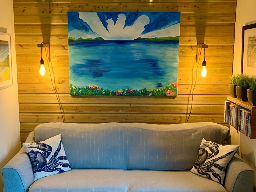 A living room with a sofa and a painting at The Studio in Feock near Truro