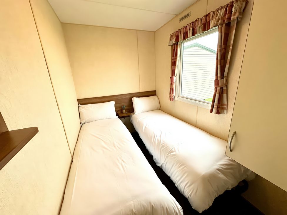 A bedroom with two single beds and a window at Chamki Lodge in Whitley Bay