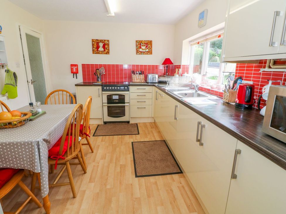 A kitchen with cabinets and appliances at The Cottage On The Green in Porthmadog