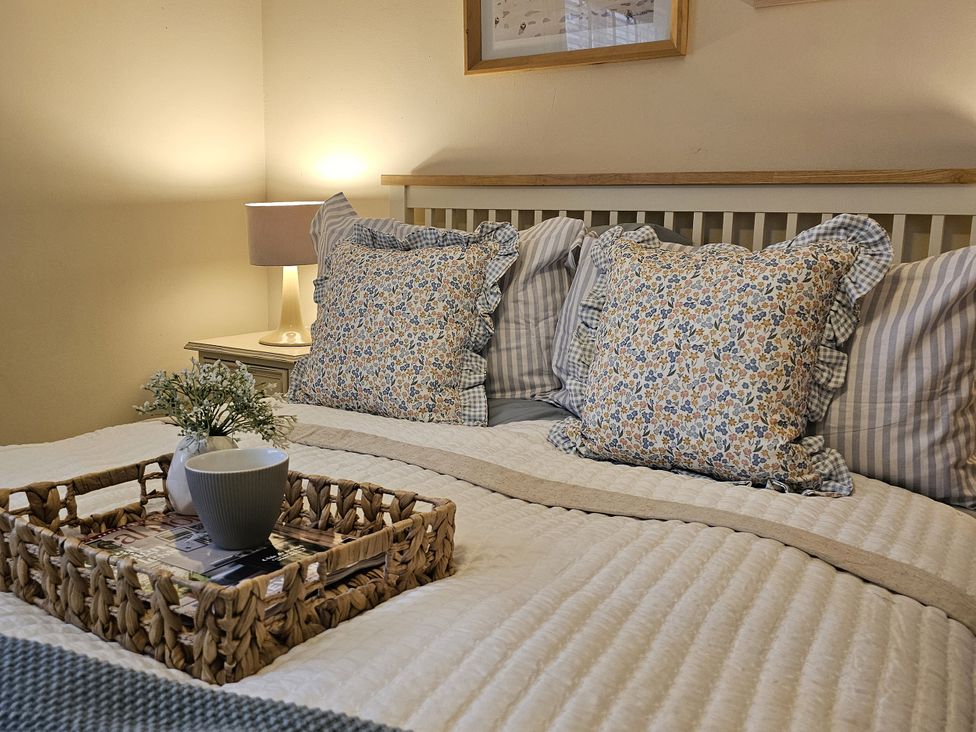 A bedroom with a bed, pillows, nightstand and a tray at The Cottage On The Green Borth-Y-Gest