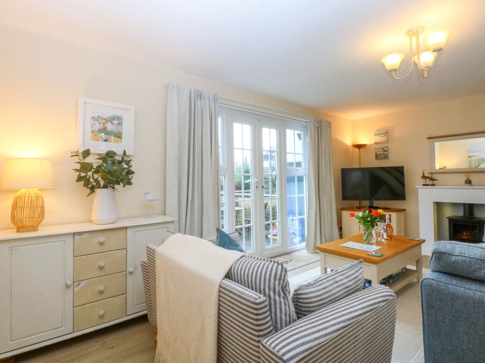 A living room with a sofa, television, and vase on the table at The Cottage On The Green in Borth-Y-Gest