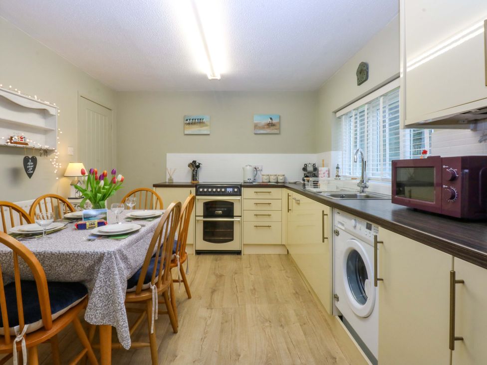 A kitchen with a dining table and various appliances at The Cottage On The Green in Borth-Y-Gest