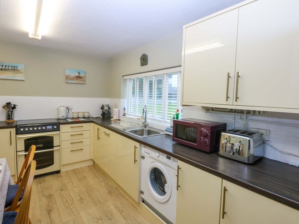 A kitchen with appliances and cabinets at The Cottage On The Green Borth-Y-Gest