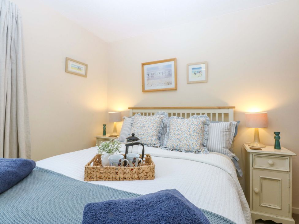 A bedroom with a bed, bedside table, and lamp at The Cottage On The Green Borth-Y-Gest